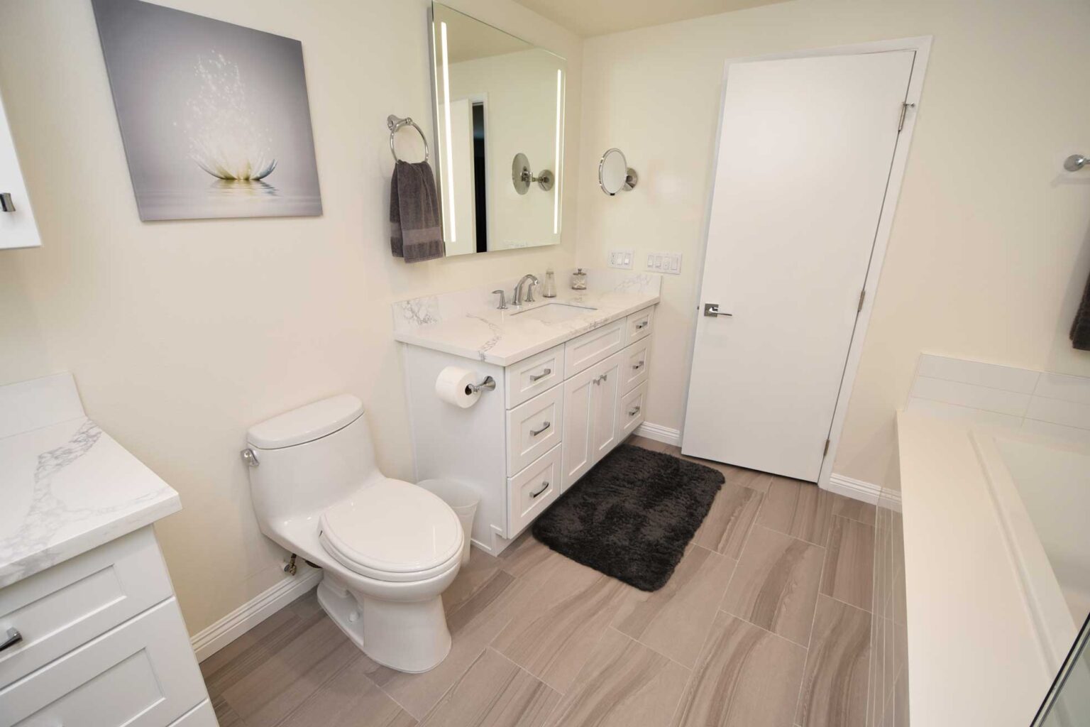 Bathroom with a white vanity, a stone top and a wood look plank floor.