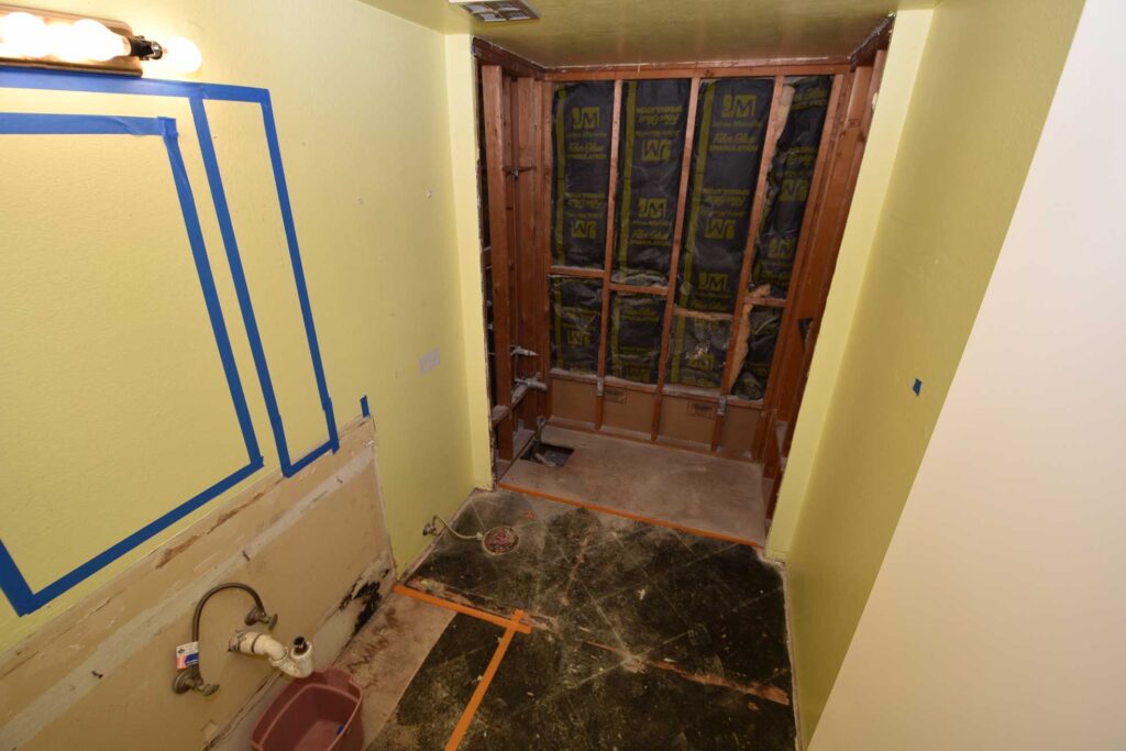 A shower alcove stripped back to the studs with wall sheeting installed, photographed before tiling.
