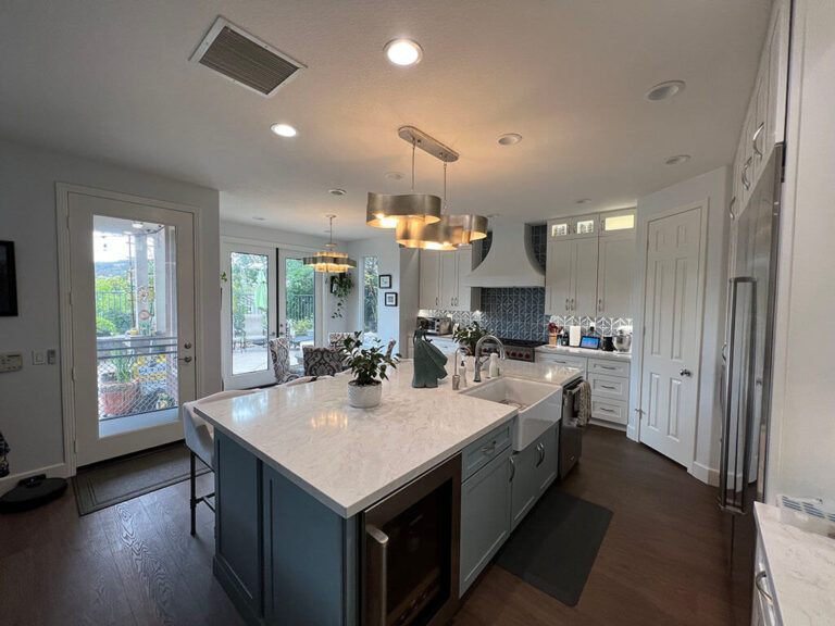 Kitchen with a navy island under a thick white stone top and a white apron front sink.