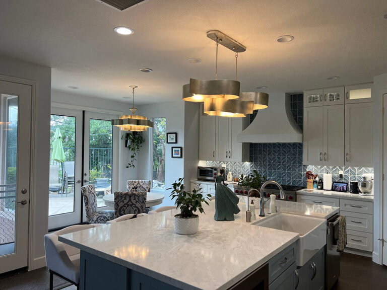 Kitchen island topped with a single pale veined slab, with a white apron front sink cut into it.