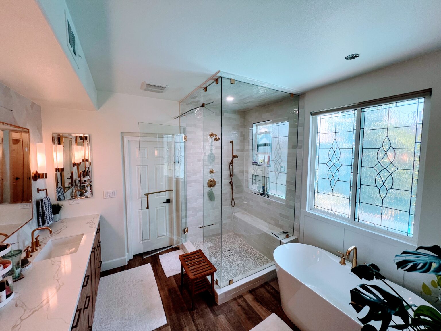 Bathroom with a glass shower, a freestanding tub and a dark wood floor.