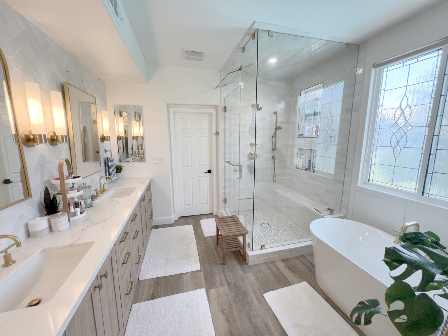 Bathroom with a long vanity, a glass walk in shower and a freestanding tub.