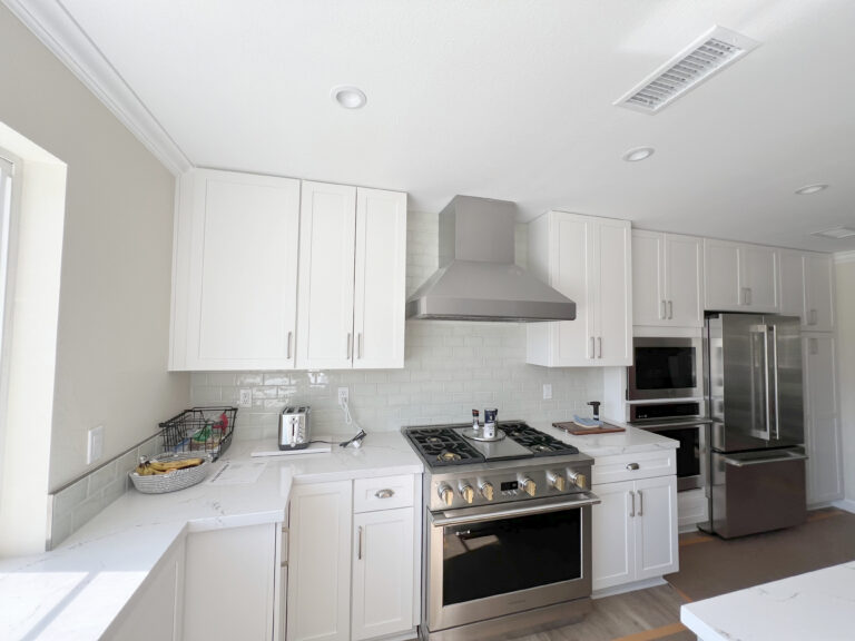 White kitchen with pale counters running along two walls beside a stainless steel range.