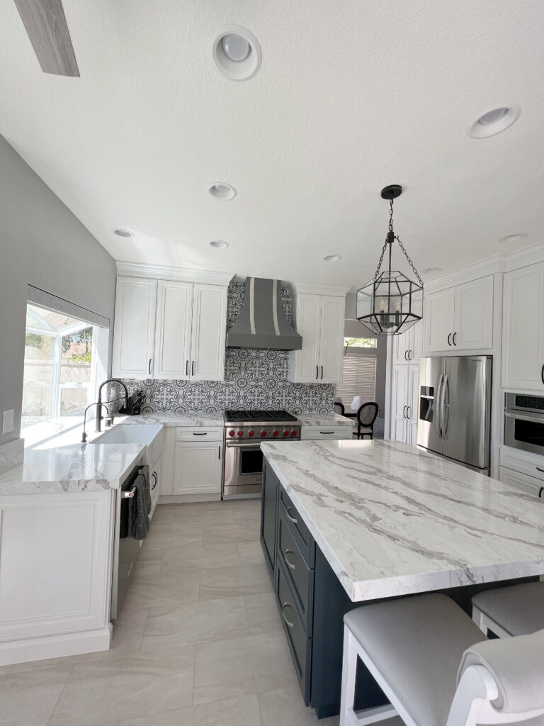 Close view of a navy kitchen island topped with white stone in heavy grey veining, with a thick squared edge.