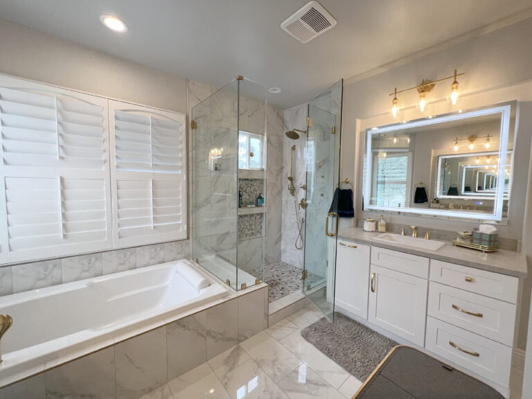 Alcove bathtub beside a glass enclosed shower, in marble look tile.