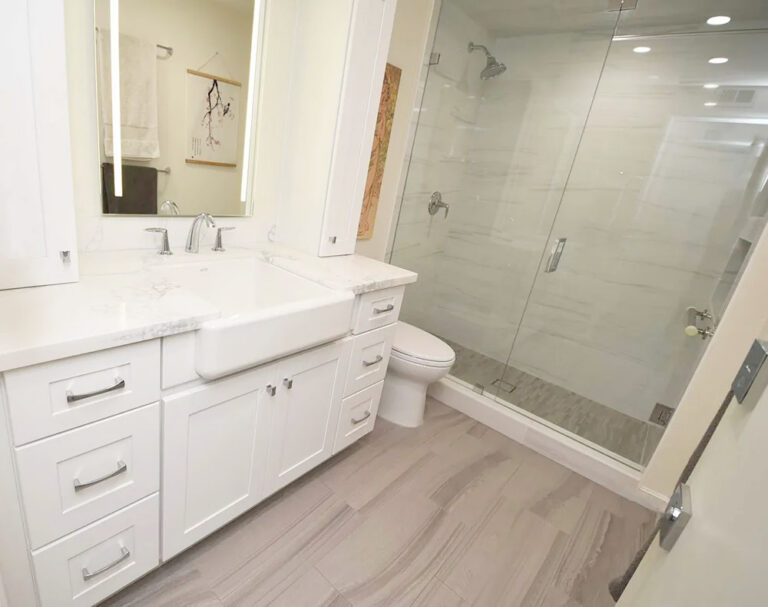 Bathroom vanity beside a walk in shower enclosed with clear glass.