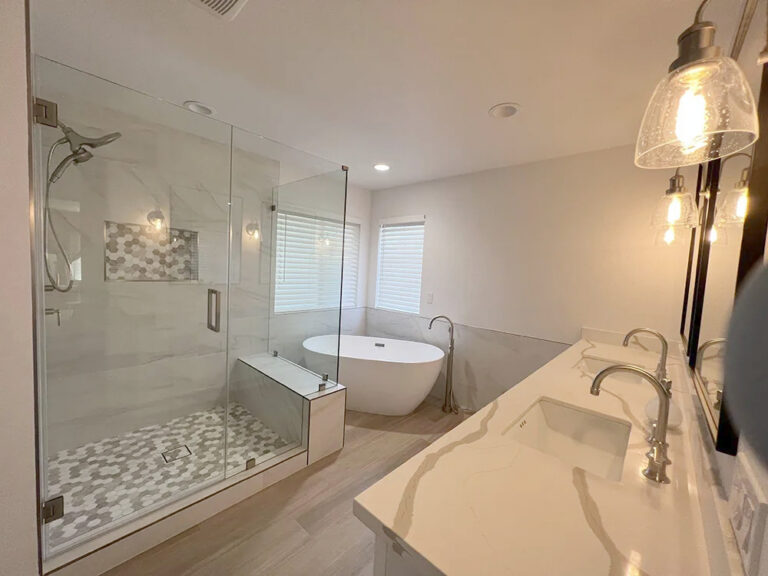 Walk in shower with a mosaic tiled floor and a recessed niche, next to a freestanding tub.