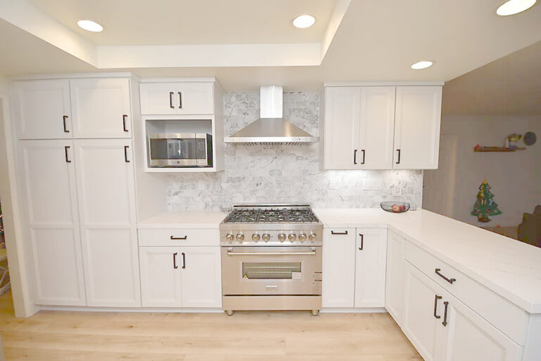 Kitchen run in white shaker cabinets, with tall pantry cabinets either side of the range.