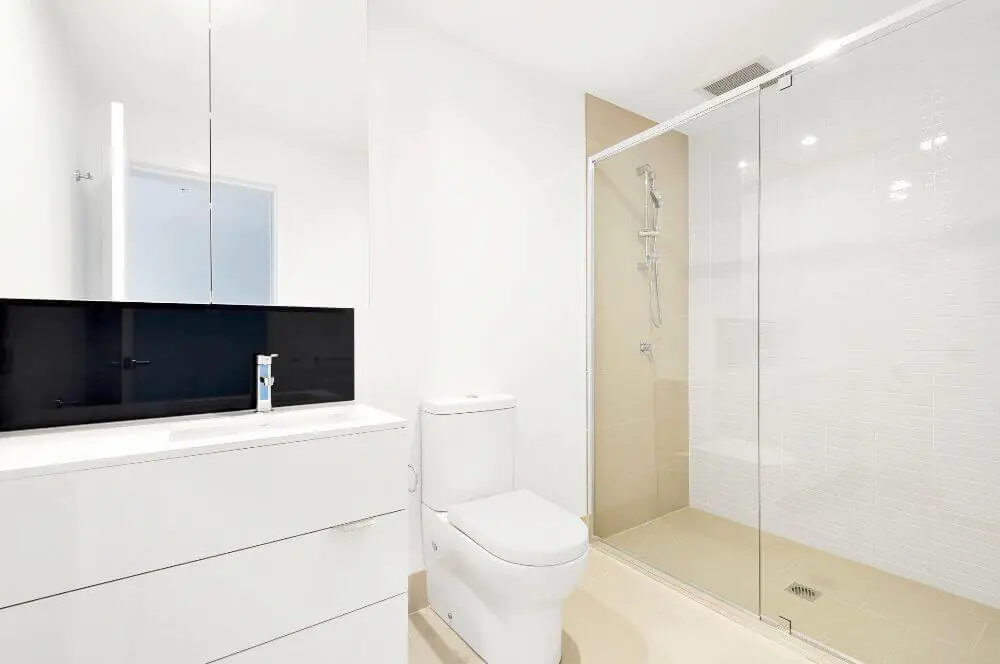 Minimal bathroom with a floating white vanity, dark backsplash panel and frameless glass shower