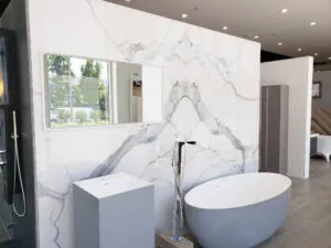 Book matched marble feature wall behind a freestanding tub, with a pedestal basin