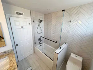 Tub and shower combination with a white herringbone tile surround and matte black fixtures