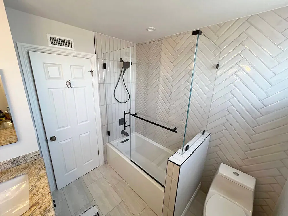 Tub and shower combination with a white herringbone tile surround and matte black fixtures