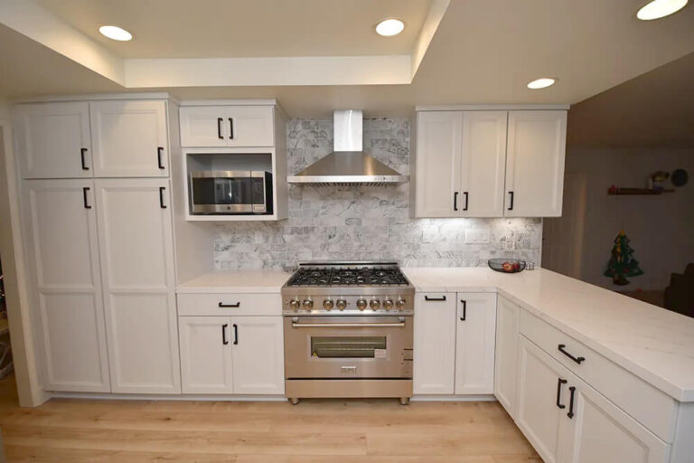 White shaker kitchen with full height pantry cabinets flanking the range.