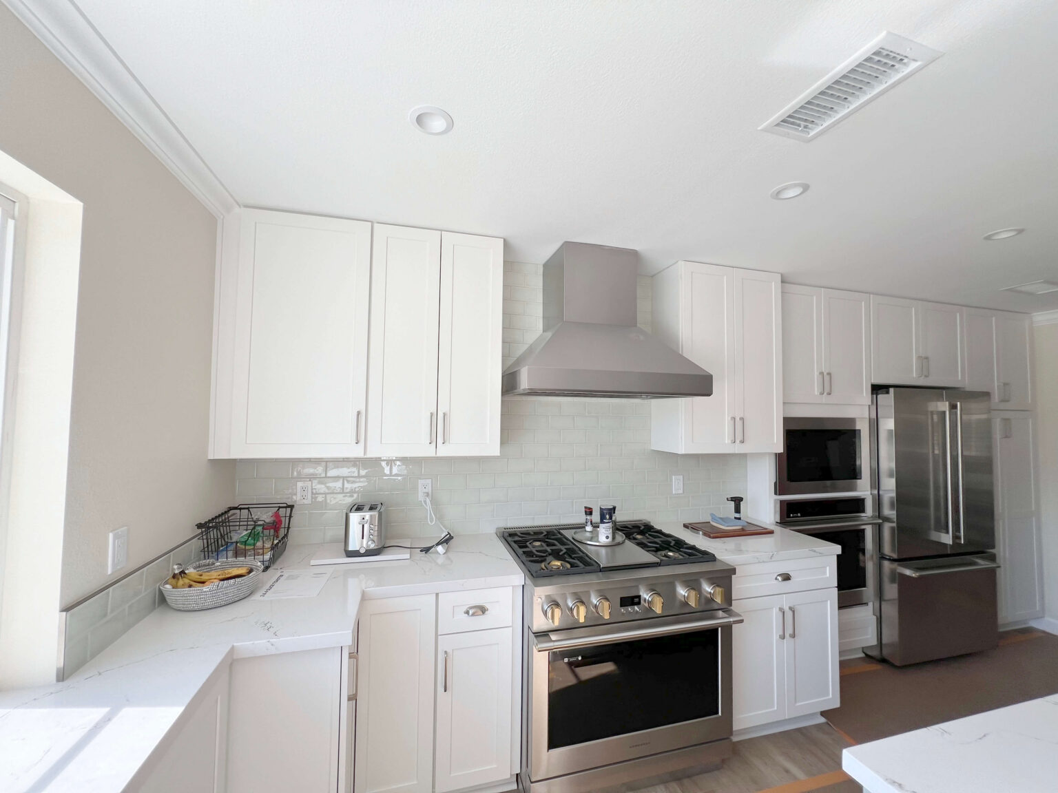 White shaker kitchen with a run of wall and base cabinets beside a stainless steel range.