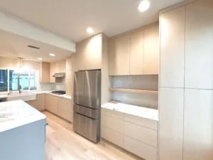 Pale oak flat panel kitchen with full height cabinetry, a marble island and a stainless refrigerator